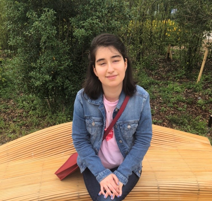 Defne Çelik, zit op een bankje in een park